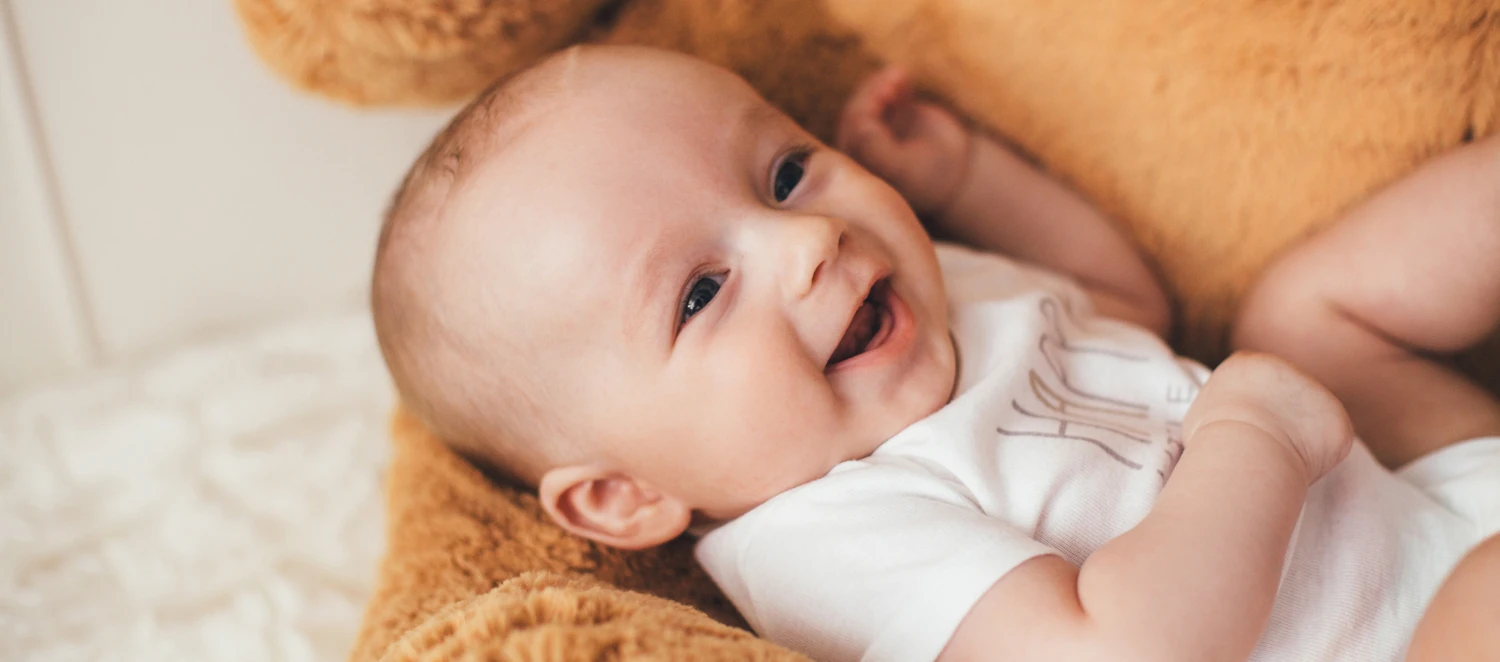 Ein Baby liegt auf einem Stoffbären